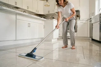 Femme utilisant un balai à plat microfibre pour nettoyer un carrelage sans traces dans une cuisine moderne