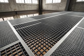 Caillebotis polyester antidérapant gris installé sur une mezzanine industrielle avec structure métallique apparente