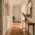 Couloir étroit décoré dans un style scandinave cosy avec console en bois, tapis en jute terracotta et miroir en laiton