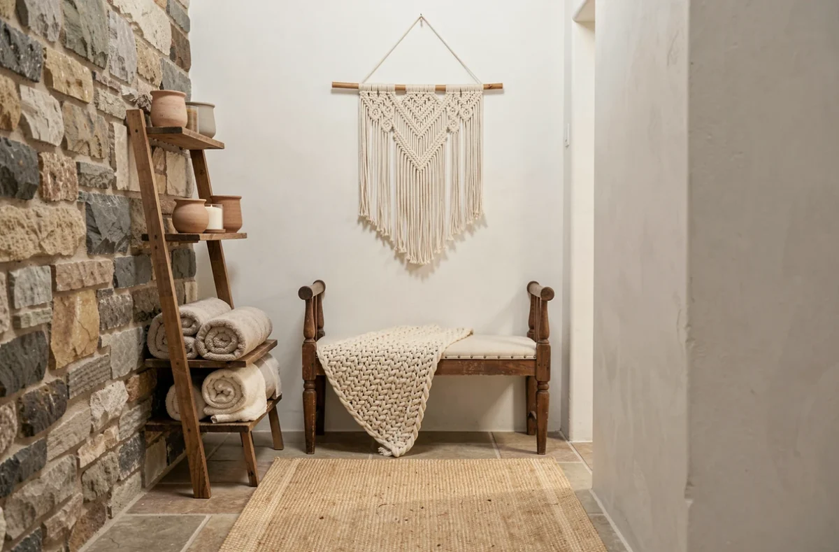 Couloir rustique avec mur en pierre apparente, banc en bois, plaid en laine et étagère échelle pour une ambiance campagne cosy