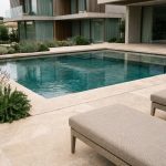Piscine sur mesure haut de gamme avec carrelage en travertin et reflets turquoise dans une villa moderne