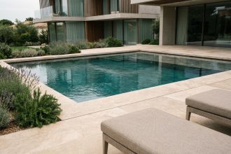 Piscine sur mesure haut de gamme avec carrelage en travertin et reflets turquoise dans une villa moderne